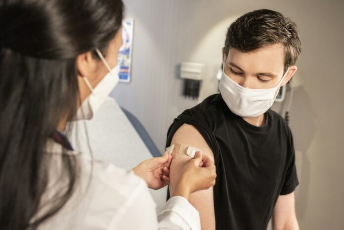 Profesional de salud coloca una curita tras aplicar una vacuna contra la influenza